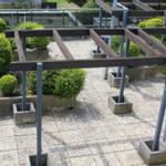 Terrasse mit Holzgestell, Pflanzen und Betonblöcken.