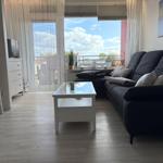 Wohnzimmer mit Sofa, Glas-Tisch und Balkonblick.