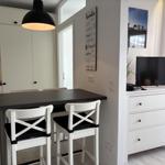 Essbereich mit Tisch, Stühlen und Küchenzeile. Fernseher auf Schrank.