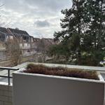 Blick von Balkon auf Wohnhäuser und Bäume unter bewölktem Himmel