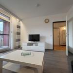 Wohnzimmer mit TV, Couch und Balkonzugang.