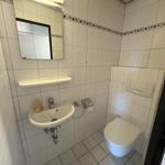 Badezimmer mit Waschbecken, Spiegel und Toilette