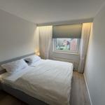 Schlafzimmer mit Doppelbett, Fenster und Nachttischlampen.