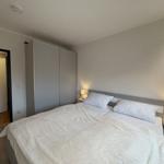 Schlafzimmer mit Doppelbett, Nachttischen und Schrank. Tür führt in angrenzenden Raum.