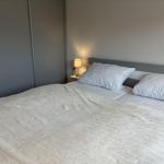 Schlafzimmer mit Bett, Kissen und Nachttischlampe. Hintergrund: Schrank und Wand.