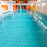 Großer Innenpool mit blauen Fliesen und moderner Beleuchtung.