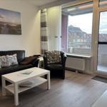 Wohnzimmer mit Sofa, Sessel und Blick auf Balkon