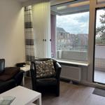 Wohnzimmer mit Sitzgelegenheiten und Balkonansicht.