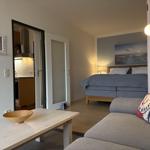 Wohnung mit Schlafzimmer, Küche und Sofa. Bett mit Kissen und Wandbild.