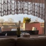 Durch das Fenster sieht man einen Balkon mit Sitzgelegenheiten und Blick auf die Landschaft.