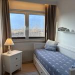 Ein Schlafzimmer mit Bett, Nachttisch und Fenster mit Blick auf Landschaft.