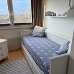 Ein Schlafzimmer mit Bett, Nachttisch und Fensterblick auf Landschaft.