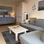 Ein Wohnzimmer mit Sofa und Bett. An der Wand hängt ein Segelbootbild.