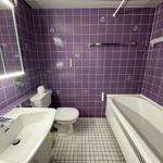 Badezimmer mit violetten Fliesen, Waschbecken, Toilette und Badewanne.