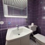 Badezimmer mit lila Fliesen, Waschbecken, Toilette und Spiegel.