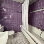 Badezimmer mit Dusche, Toilette und Waschbecken. Wandfliesen sind lila.