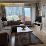 Wohnzimmer mit Sofa, Couchtisch und TV. Balkon mit Blick.