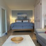 Schlafzimmer mit Bett, Couch und Wandbild. Helle Holzböden und weiße Möbel.