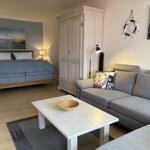 Schlafzimmer mit Bett, Sofa und Kleiderschrank. Wanddekoration und Holzboden.