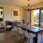 Dining room with table, chairs, and balcony view. Red chandelier and wall art.