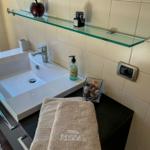 Sink with mirror, towel, and soap on dark vanity.