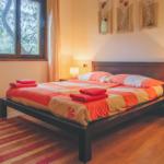 Bedroom with bed, nightstands, and window overlooking trees.