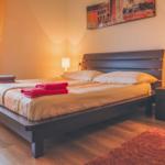 A bedroom with a bed, nightstand, and window. Towels are on the bed.