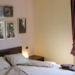 Bedroom with bed, wall pictures, and window with view of trees.