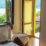 Room with view of lake and mountains, balcony, bed and radiator.