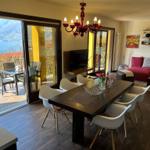 Dining room with lake and mountain view. Living area with red sofa.