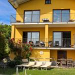 Yellow house with pool, sun loungers, and balconies. Red roses on the wall.