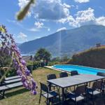 Pool area with table, chairs, and view of lake and mountains.