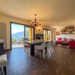 Living and dining area with balcony, red sofa, and dining table with chairs.