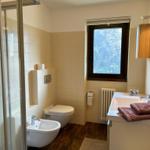 Badezimmer mit Dusche, Toilette, Waschbecken und Fenster.