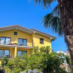 Gelbes Haus mit Balkonen und Palme vor blauem Himmel