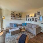 Wohnzimmer mit Ecksofa, Wandregalen und Bildern an der Wand.