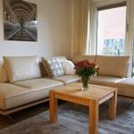 Wohnzimmer mit L-förmigem Sofa, Holztisch und Blick auf Balkon