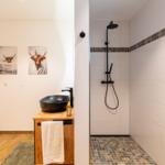 Bad mit Dusche, Waschbecken und Wandbildern von Highland-Rindern.