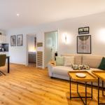 Wohnzimmer mit Sofa, Tischen und Blick in Küche und Schlafzimmer.