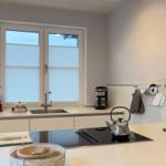 Küche mit Arbeitsplatte, Spüle und Fenster mit Jalousien.
