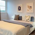 Schlafzimmer mit Bett, Fenster und Wandbildern.