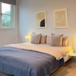 Schlafzimmer mit Bett, Fenster und Wandbildern.