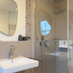 Badezimmer mit Waschbecken, Spiegel und Dusche.