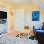 Schlafzimmer mit Bett, Sofa und Fernseher an der Wand.