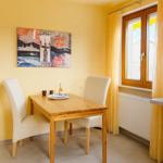 Esszimmer mit Holztisch, zwei Stühlen, Wandbild und Fenster.