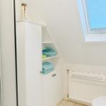 Badezimmer mit Dachschrägen, Schrank, Duschabtrennung und Toilette.