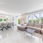 Großes Wohn- und Esszimmer mit Sofa, Tisch und Fenstern.