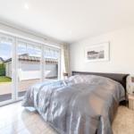 Schlafzimmer mit Bett, Schrank und Blick auf die Terrasse.