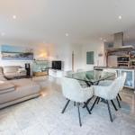 Wohn- und Essbereich mit Sofa, Glas-Tisch und moderner Küche.