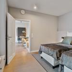 Two beds with blankets and pillows. Hallway to dining area with table and chairs.